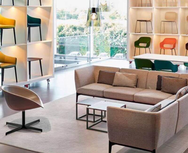 Spazio moderno con divani eleganti, sedie colorate e luce naturale vibrante.